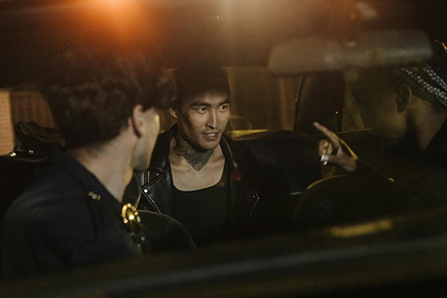 Man in Black Leather Jacket Sitting inside a police car with officers