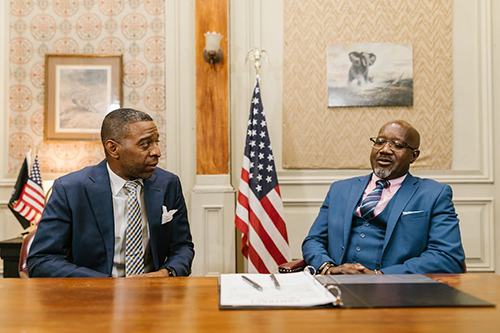 Men in Business Suit Sitting at a Table Looking at Papers