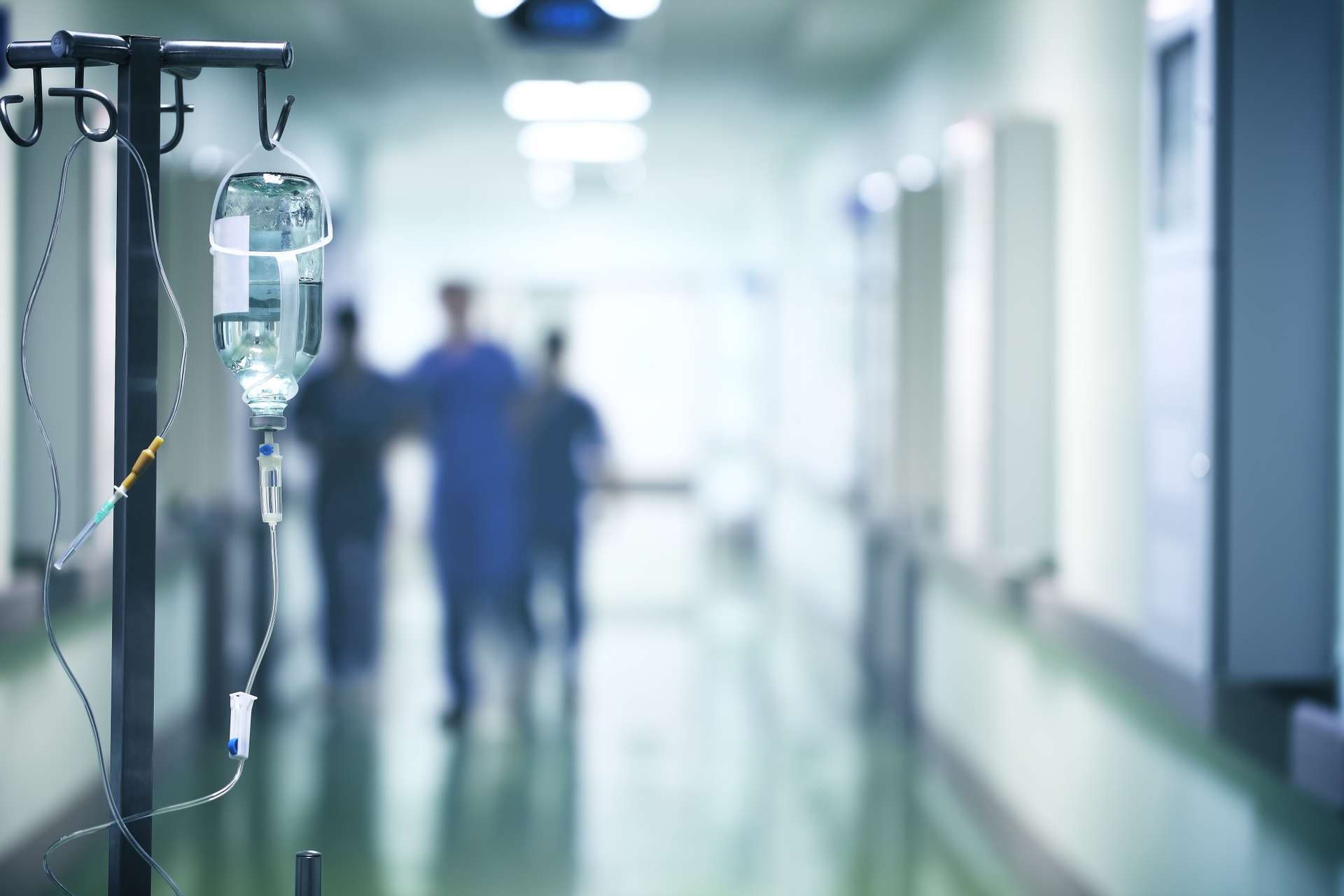 An IV stand in a hall with medical professionals